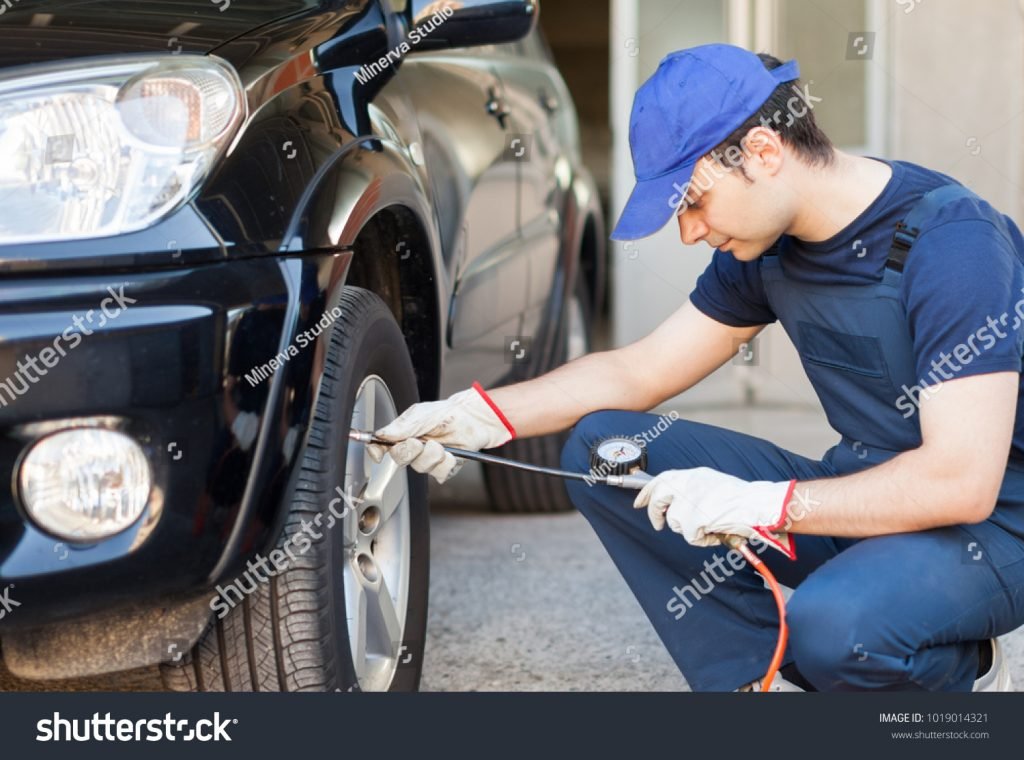 A person inflating the tire of a car with help of air compressor.